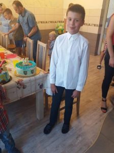 Chłopiec stoi obok urodzinowego stołu