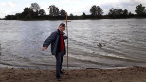 chlopiec stojący z krzyżem przy jeziorku
