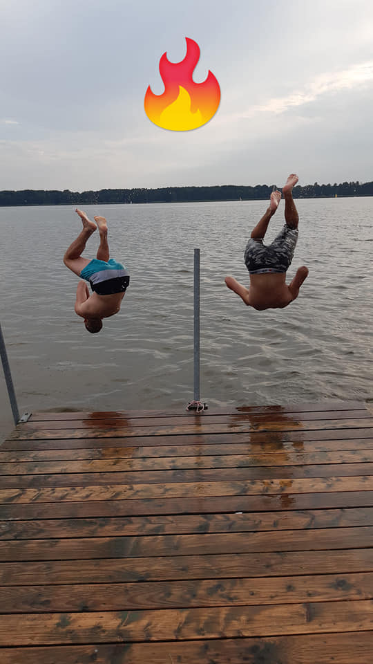 Dwoje chłopców skacze do wody robiąc fikołki