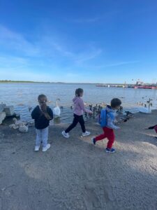 trójka dzieci na plaży wśród ptaków