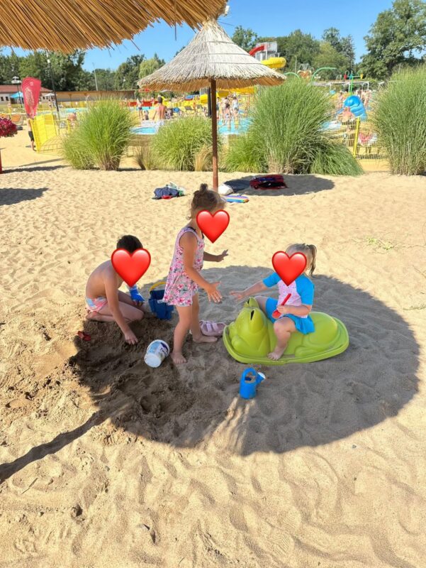 trójka dzieci na plaży w słoneczny dzień, pod parasolem